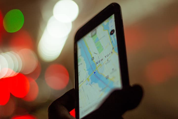 móvil con mapa de nueva york en la pantalla, al fondo luces desenfocadas - weroad