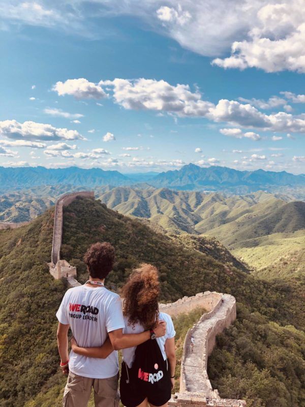 dos viajeros weroad de espaldas, abrazándose, encima de la gran muralla china y mirando el paisaje