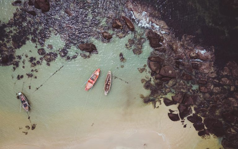 foto aerea de una playa de phu quoc con barcos y rocas negras - weroad