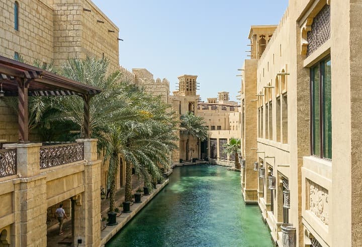 souk madinat jumeirah en dubái, edificios, un canal con agua y palmeras - weroad