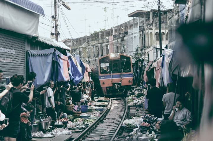 tren pasado en medio de puestos de venta en el mercado en tailandia - weroad