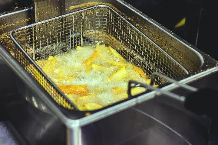 patatas friéndose en una freidora con el aceite hirviendo - weroad