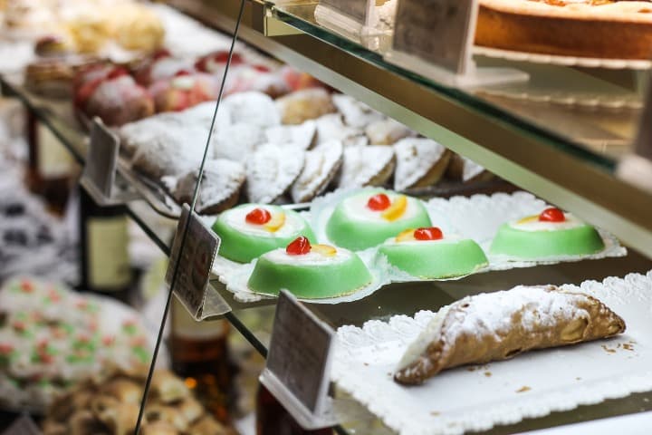 vitrina de una panaderia con en muestra dulces sicilianos: cassatas y cannolo - weroad