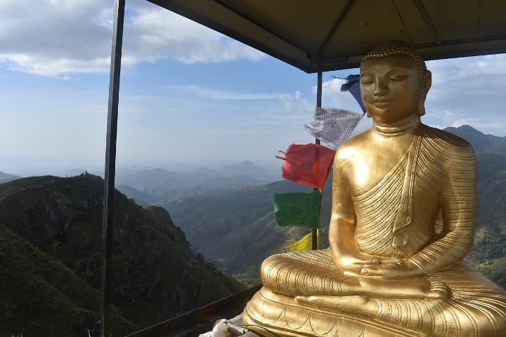 estatua durada de buda en el adam's peak o pico de adan en sri lanka, dentrás montañas y banderas coloridas - weroad