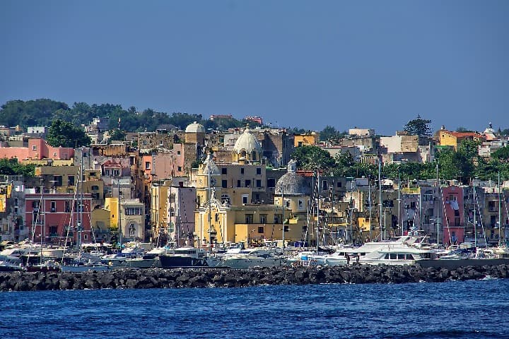 isla de ischia, una de las excursiones desde nápoles, vista desde el mar. casas bajas de colores y barcos en el puerto - weroad