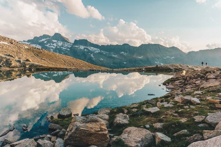 cielo y nubes reflectandose en un lago en medio de las montañas de val d'aosta, italia, donde ir de vacaciones en agosto - weroad