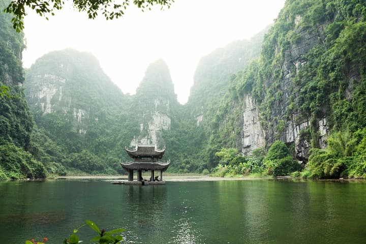 templo en medio a agua con detrás vegetación verde en vietnam, destino para viajes para solteros - weroad