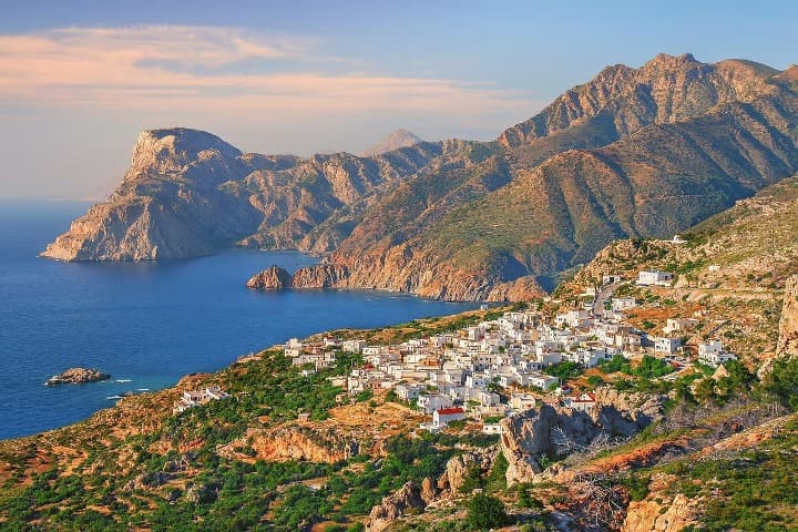 panorama de un pueblo en la ladera de una montaña en una de las la islas de grecia, karpathos, al fondo mar y montaña - weroad