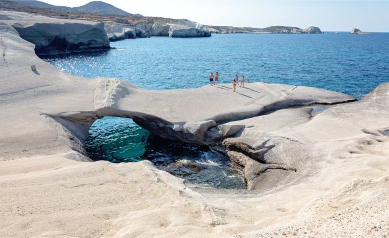 una playa de roca lisa con un arco a través del cual se ve el mar en sarakiniko, en una de las islas de grecia, milos - weroad