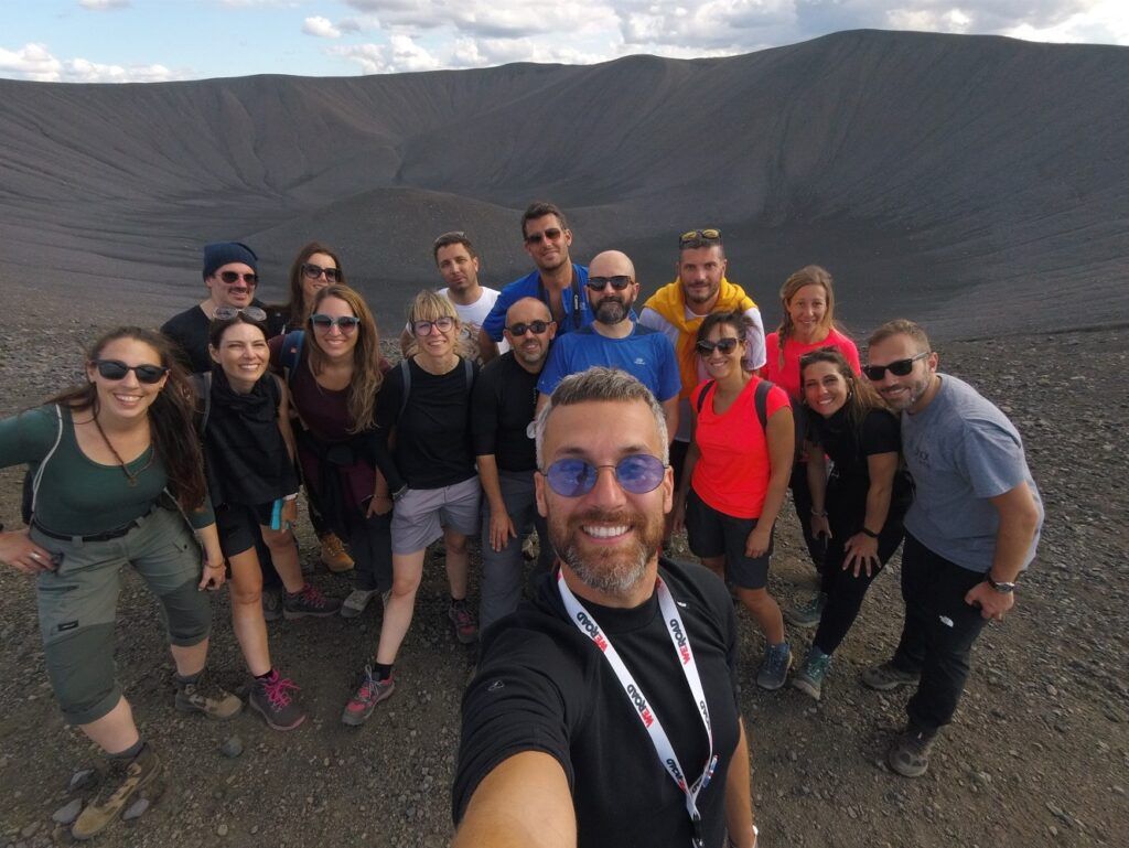 que ver en islandia, selfie por parte de un coordinador weroad con detràs grupo de viajeros y de fondo un crater de un volcán en islandia