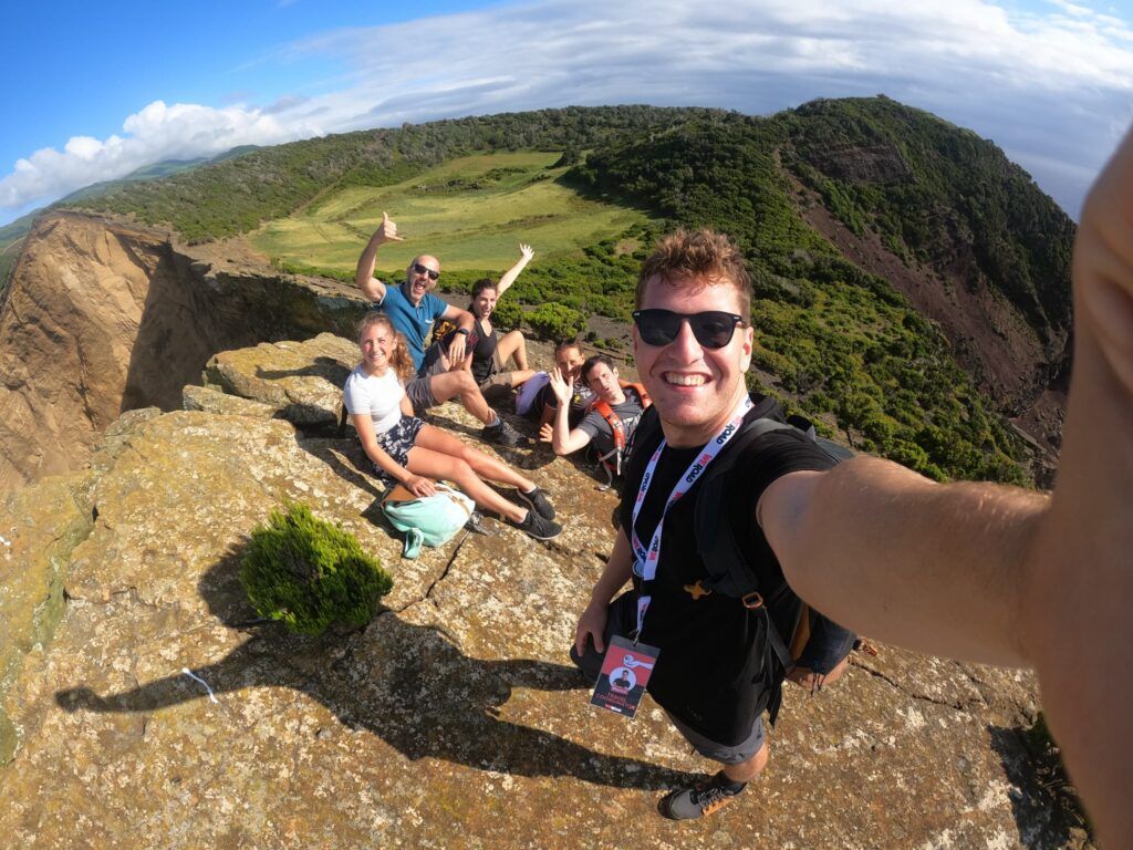selfie de grupo de viajeros weroad en azores, lugar que ver en portugal. detrás montañas verdes