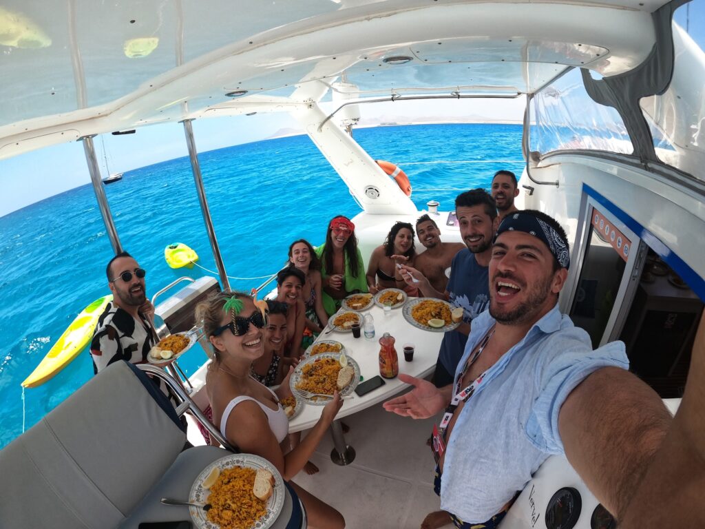 selfie de grupo de viajeros weroad en un barco en fuerteventura comiendo paella, uno de los viajes organizados por españa