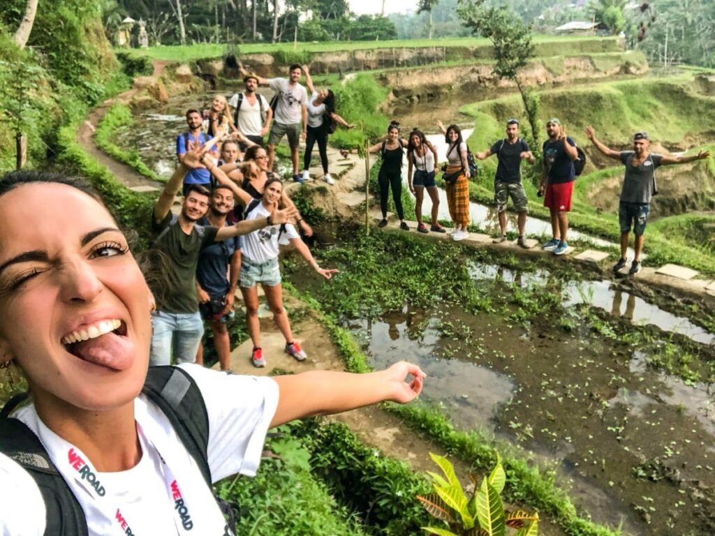 selfie de coordinadora weroad con detrás otros viajeros en un arrozal en indonesia