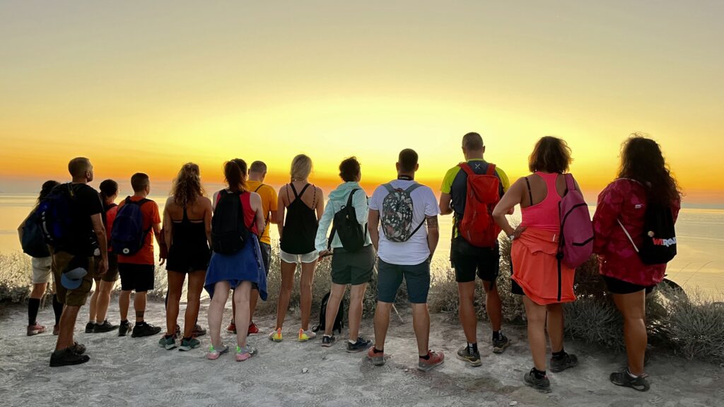 grupo de viajeros weroad fotografiados de espaldas mientras admiran una pursta del sol en las eolias, sicilia