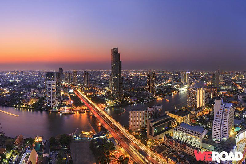 vista aerea de la ciudad de bangkok al atardecer con edificios iluminados y rio - weroad