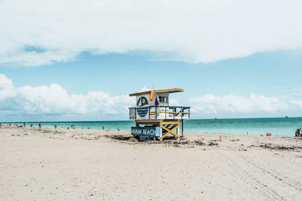 playa de miami beach, al centro una cabina de salvamento azul, blanca y amarilla, mar al fondo - weroad