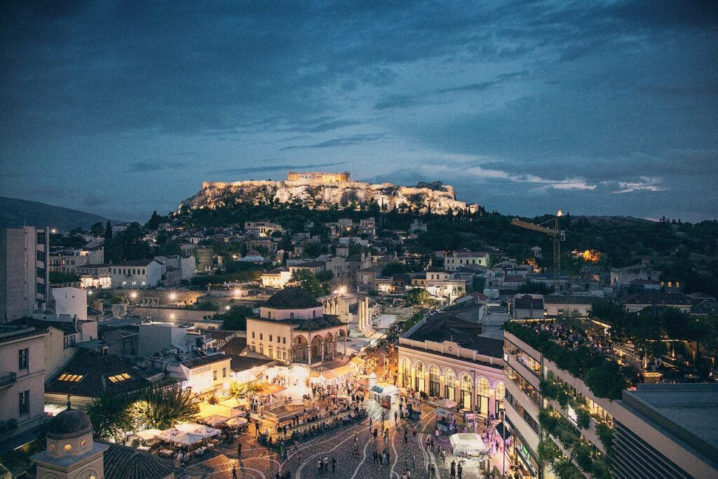 ciudad de atenas de noche, al fondo se aprecia el partenone elevado e iluminado, algo que ver en grecia continental, weroad