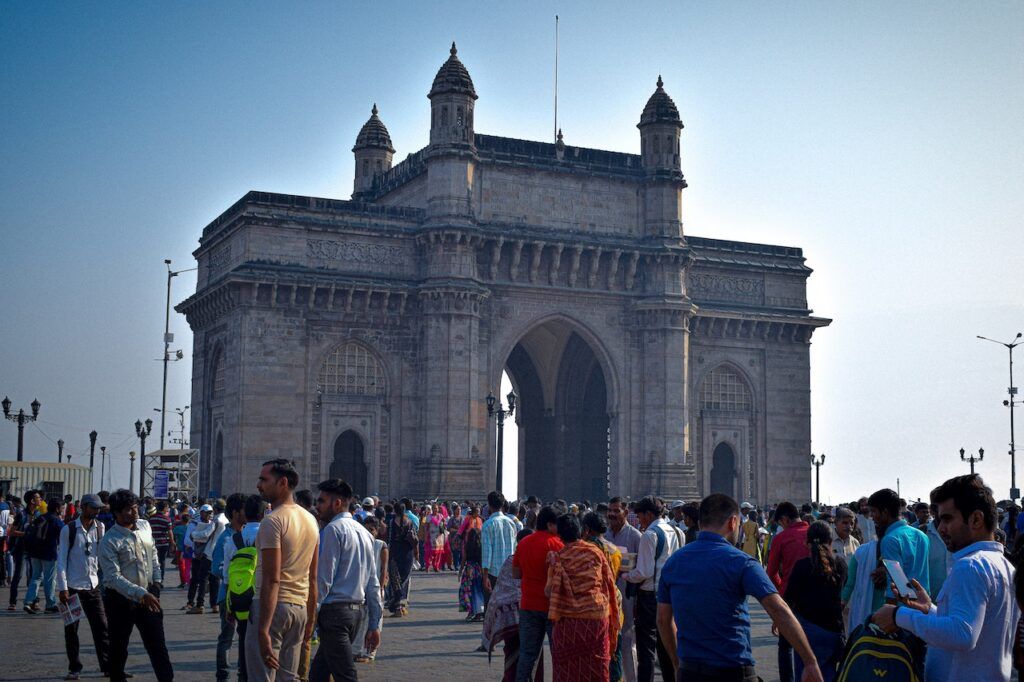 inmenso arco, el portal de la india en mumbai, con delante personas paseando en la plaza - weroad