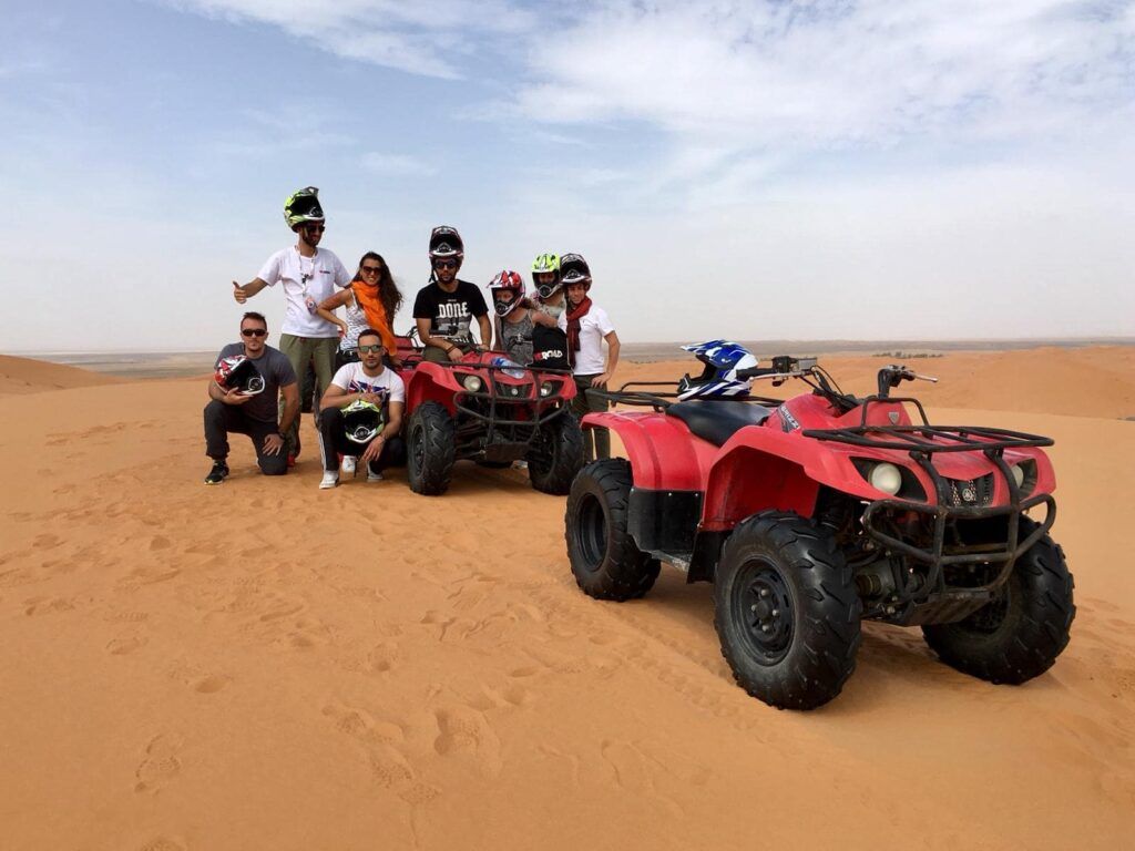 grupo de viajeros weroad en el desierto de marruecos con quad y cascos, destino al que viajar en otoño