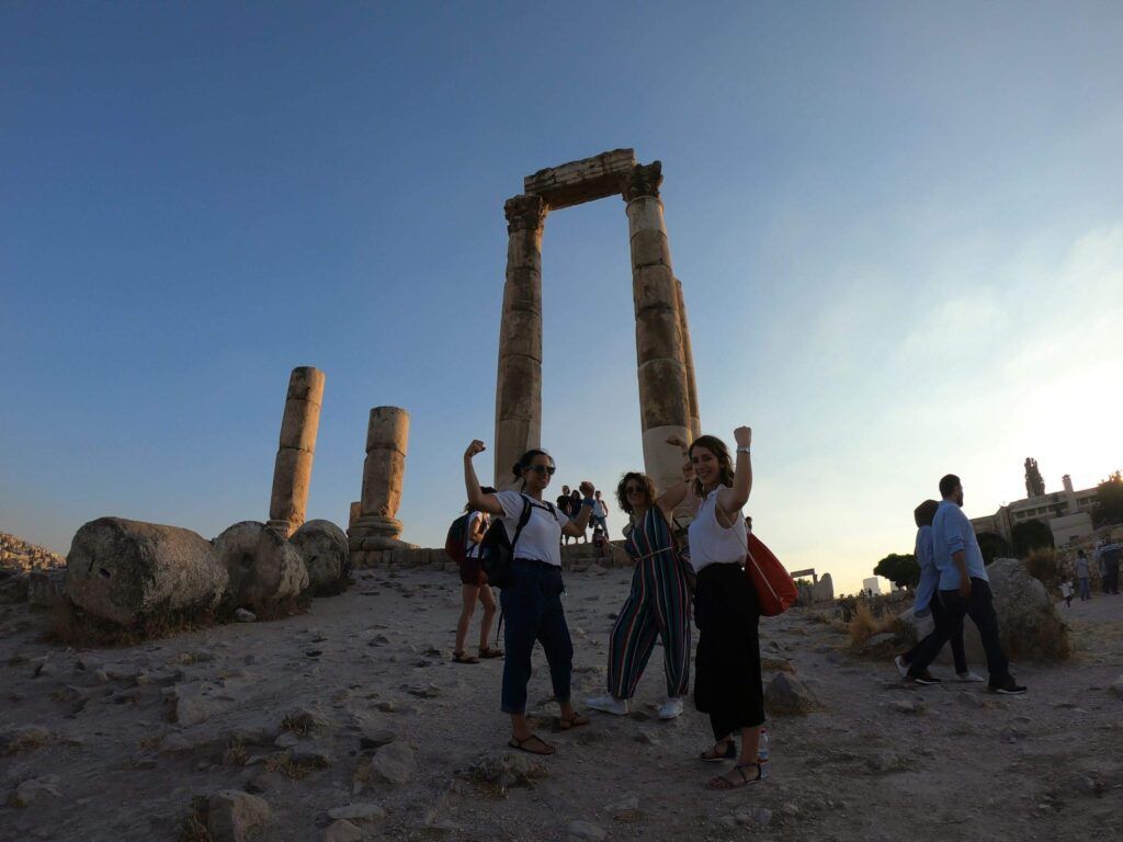 chicas de weroad levantando el brazo delante de restos del templo de hercules en ammán
