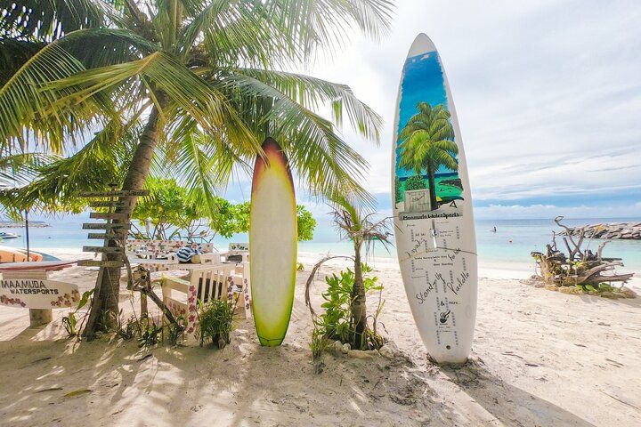 tablas de surf plantadas verticalmente en la arena en la playa de maafushi, surfear es algo que hacer en maldivas - weroad