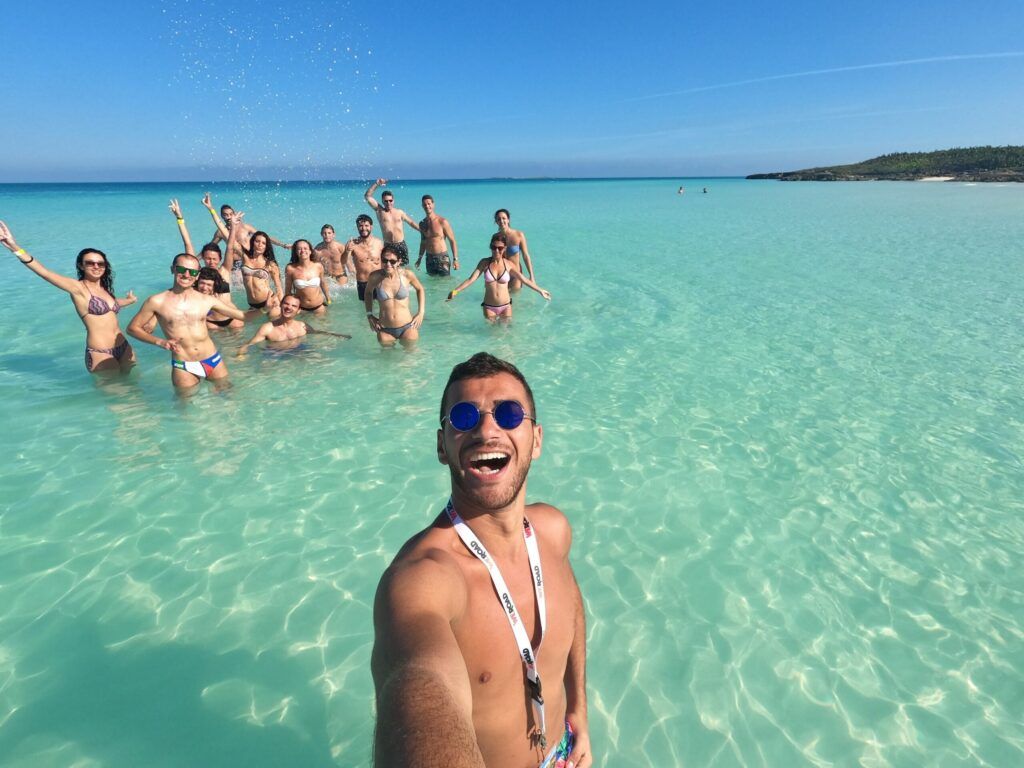 tour leader sacando un selfie en el agua de una playa cubana con detrás un grupo de viajeros