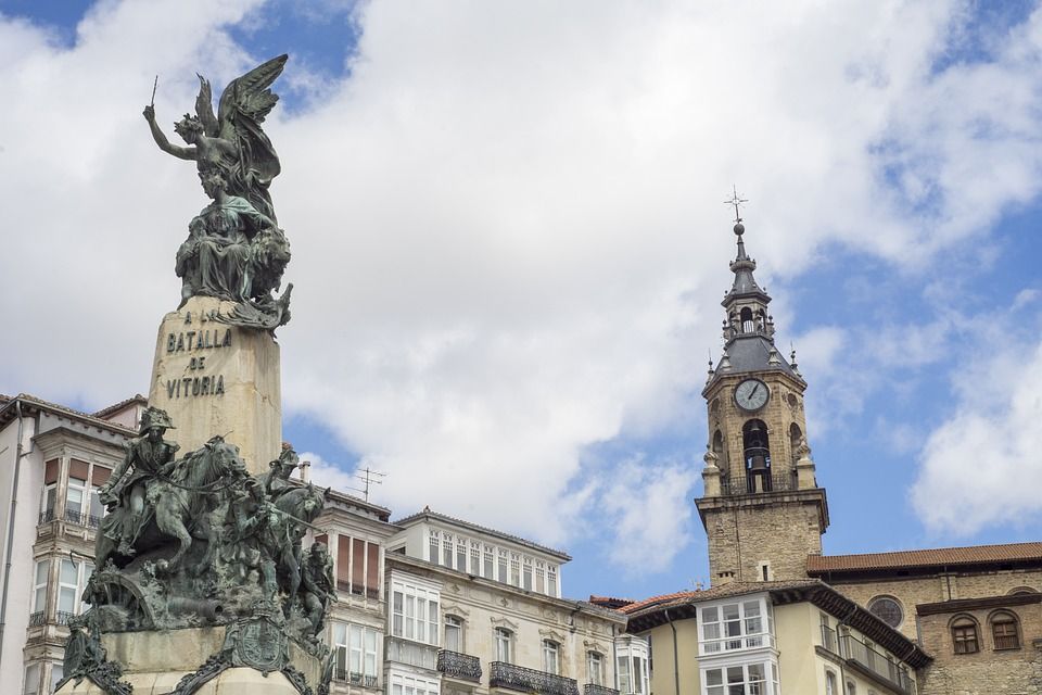 campanario, edificios y estatua en el centro de vitoria, en el país vasco - weroad