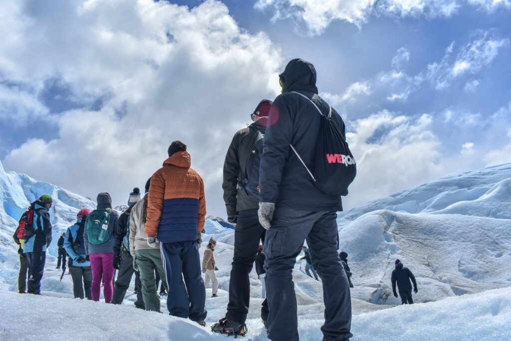 viajeros de weroad de espaldas en medio de un glaciar en patagonia, destino que visitar durante los festivos 2023