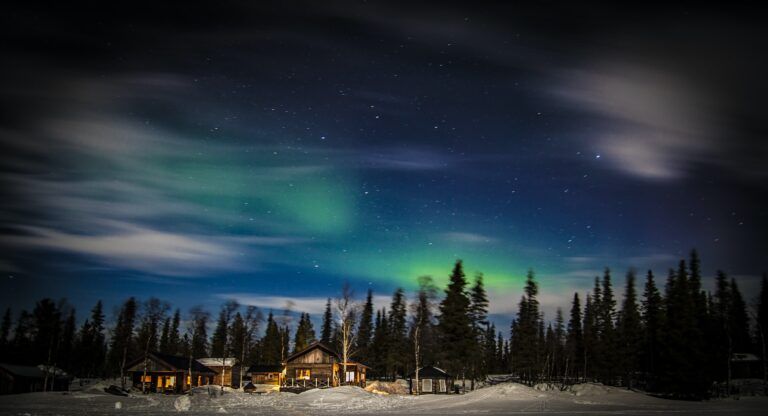 arboles y casitas y la aurora boreal en el cielo, algo que ver en suecia - weroad