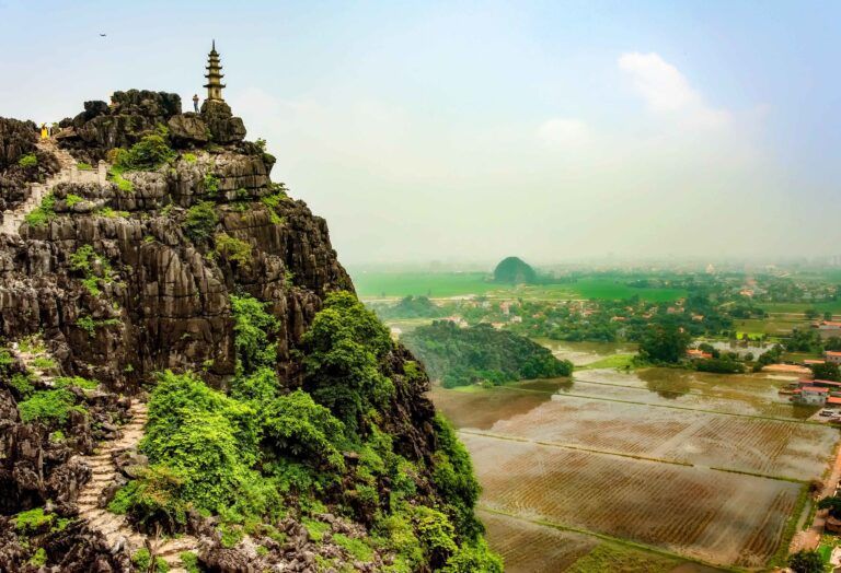 montaña verde con templo encima y vista aerea de paesaje verde en las mua caves en Vietnam