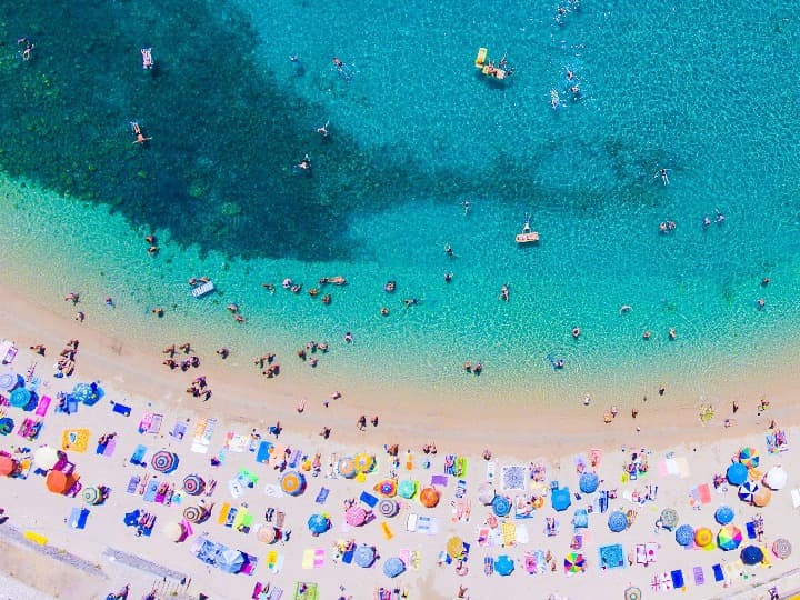 vista zenital de una playa de corfu, agua azul y sombrillas en la playa - weroad