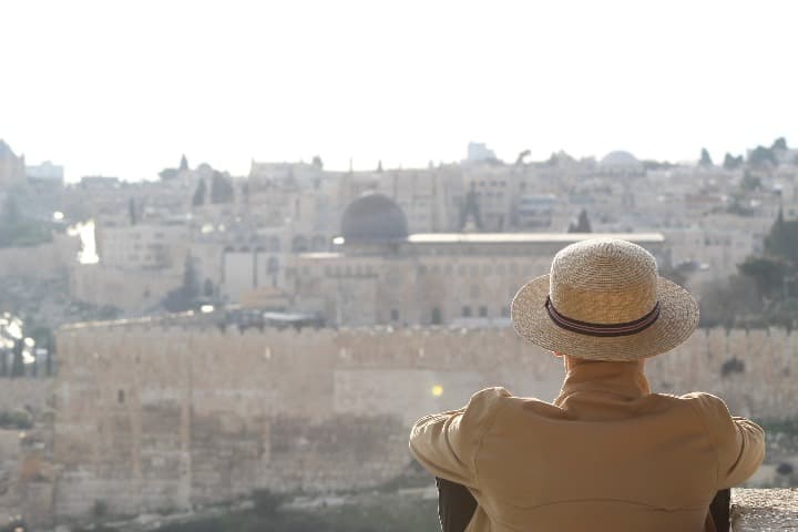 hombre de espaldas con sombrero de paja admirando la vista desde el monte de los olivos, ciudadela de piedra - weroad