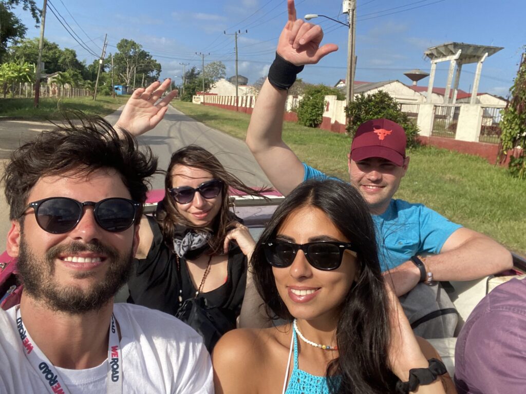 selfie de cuatro viajeros weroad sentados en un coche antiguo descapotable en cuba, destino a donde viajar en abril