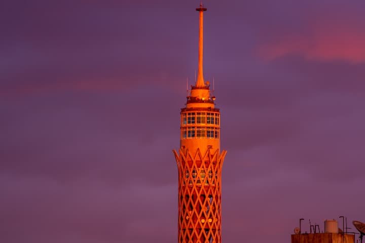 torre de el cairo iluminada por la luz del ocaso, detrás cielo lila - weroad