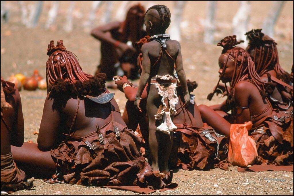 niños y mujeres de la tribu himba, de espaldas y cubiertos de tierra roja - weroad