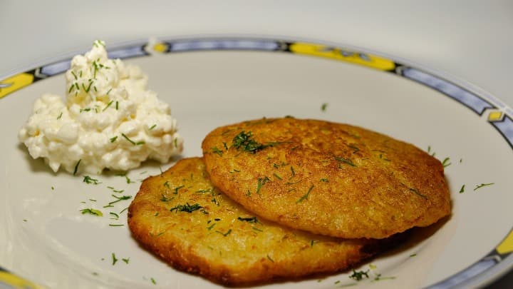 latke, 2 croquetas de patatas con puré de algo blanco al lado, en un plato - weroad