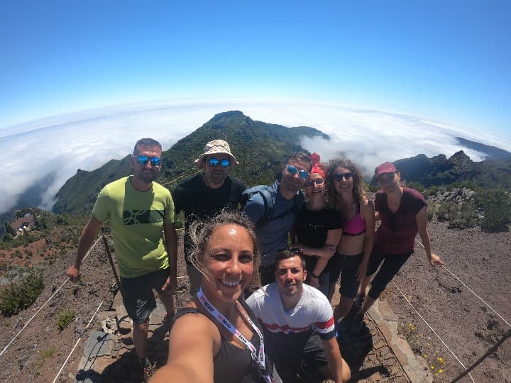 selfie de viajeros weroad encima de una montaña en madeira, nubes detrás