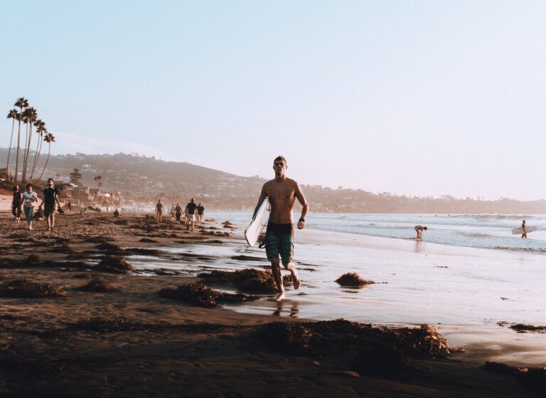surfero saliendo del agua con tabla bajo el brazo en playa de la jolla, algo que ver en san diego - weroad