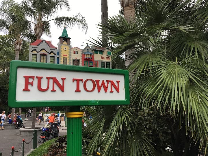 señal con escrito fun town en legoland, detrás edificios con estilo lego y palmeras - weroad