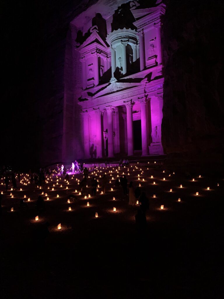 edificio tesoro iluminado de rosa, delante centenares de velas y beduinos tocando instrumentos - weroad