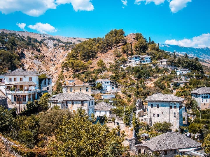 ciudad de Gjirokastër, casas en piedra desperdigadas por la ladera de una montaña, cielo azul detrás, albania - weroad