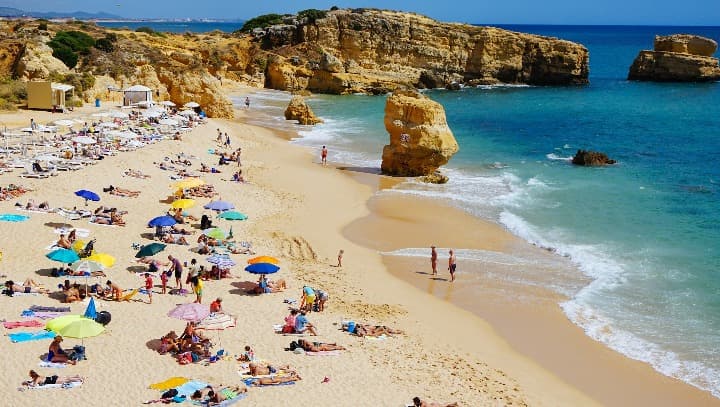 Praia de São Rafael, Albufeira, Portugal, gente con sombrillas de colores, rocas y mar - weroad