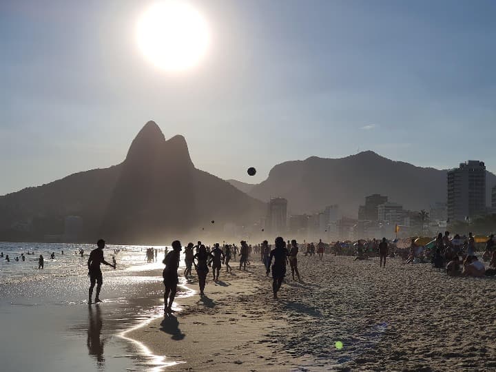playa de ipanema, chicos jugando con un balon, al fnondo montañas y el sol - weroad