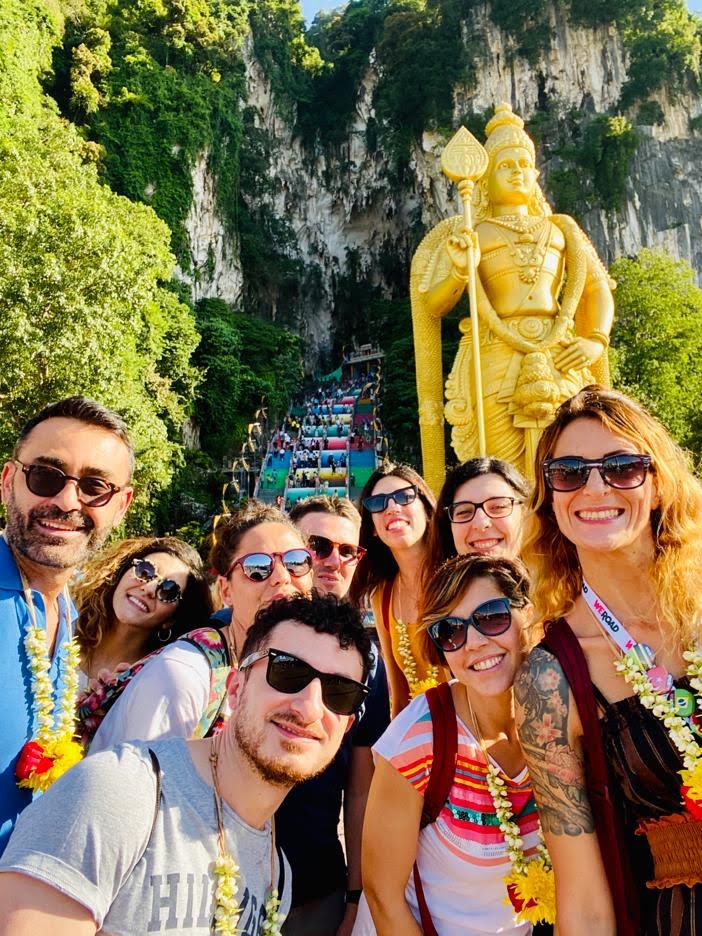selfie de grupo de viajeros weroad delante de una estatua dorada en malasia, destino que a donde ir en septiembre
