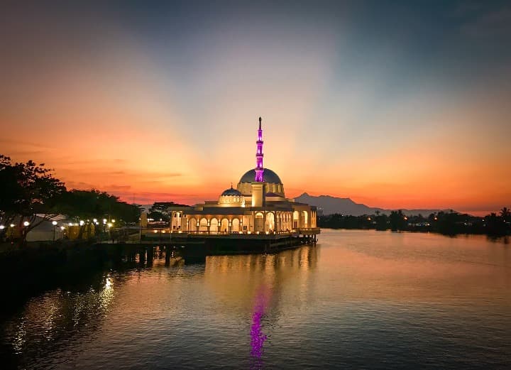 mezquita dorada con puesta del sol naranja detrás en Kuching, malasia - weroad