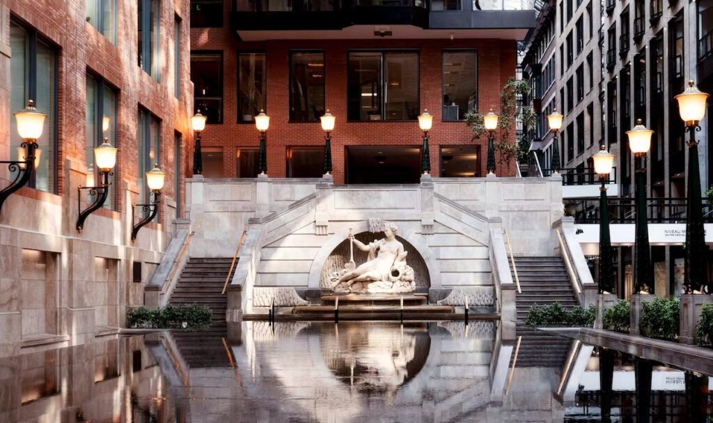 edificio en montreal con escaleras delante de los lados y estatua en el centro, extensión de agua en la que se refleja esta fachada. ciudades subterráneas - weroad