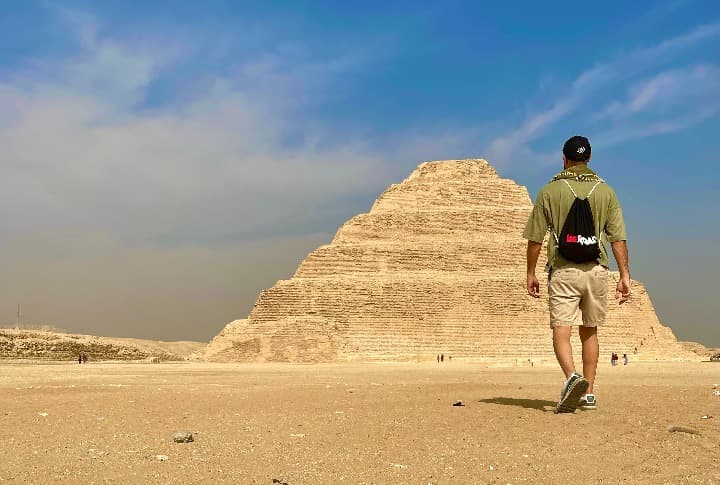 viajero weroad de espaldas con mochila corporativa caminando hacia una piramide en egipto