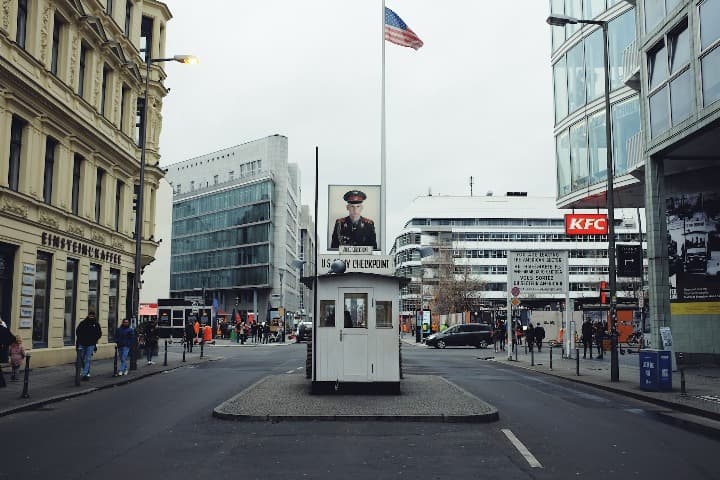 checkpoint charlie con bandera americana, edificos detrás, berlin
