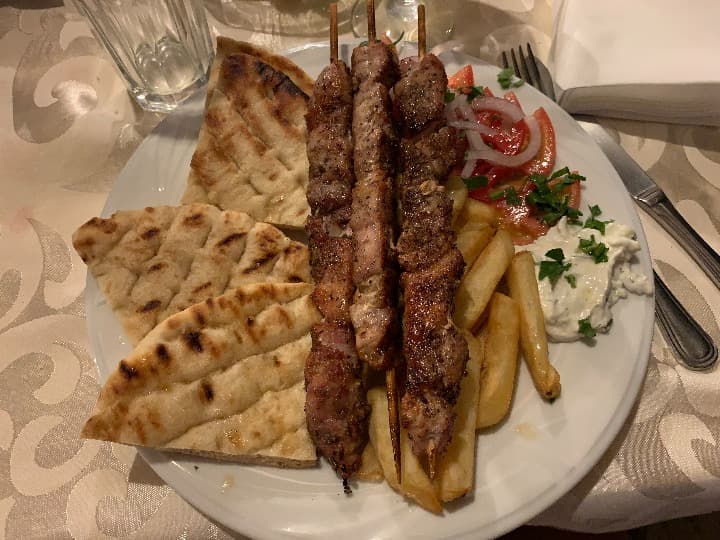 souvlaki, brocheta de carne encima de pan pita y patatasa, algo que comer en grecia