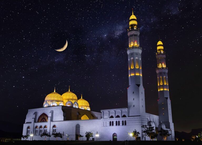 mezquita iluminada en la noche, cielo con luna y estrellas detrás
